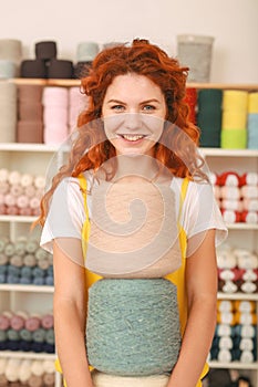 Red-haired beaming girl holding three big colorful clews