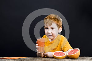 Red-haired boy with citrus fruits on the table