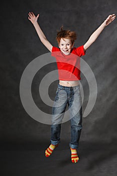 Red-haired boy jumping on a dark background. Studio photography