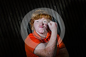 Red-haired boy showing biceps with threaten face