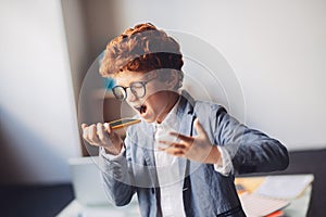 Red-haired boy in a suit shouting something while talking by phone