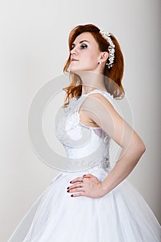 Red-haired bride in a wedding dress, bright unusual appearance. Beautiful hairstyle and professional make-up