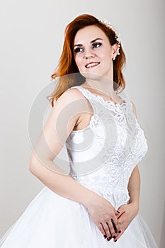 Red-haired bride in a wedding dress, bright unusual appearance. Beautiful hairstyle and professional make-up