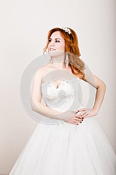 Red-haired bride in a wedding dress, bright unusual appearance. Beautiful wedding hairstyle and bright make-up