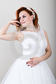 Red-haired bride in a wedding dress holding wedding bouquet, bright unusual appearance. Beautiful wedding hairstyle and