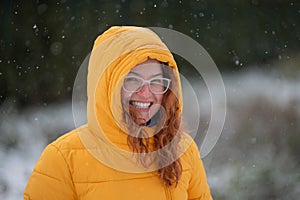 Red-haired Caucasian woman rejoices at the first snow.