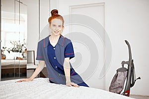 A female chambermaid making bed in hotel room