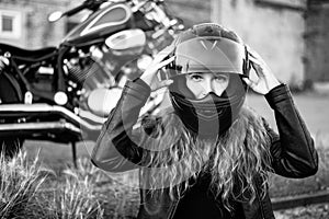 Red-haired curly woman in a helmet near a motorcycle. Monochrome.