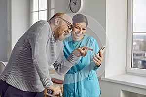 Red-haired, elderly bearded man with caring nurse are laughing and having fun in a nursing home.