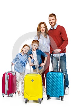 red haired family with suitcases standing together and smiling at camera