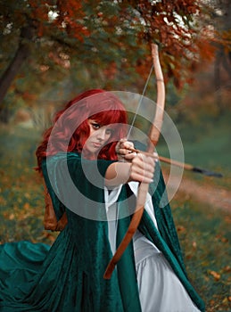 Red-haired fiery robber in moment before attack, the legend of Robin Hood, girl is holding a bow and arrow in her hands