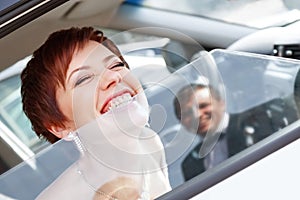 Red-haired funny bride in the car smiling groom. Woman 35 years. Wedding