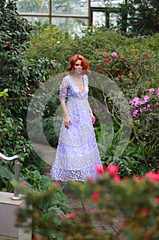 Red-haired girl in arranger where azalea blooms in a colorful flying dress