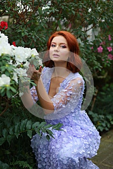 Red-haired girl in arranger where azalea blooms in a colorful flying dress photo