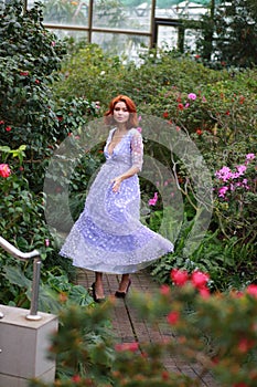 Red-haired girl in arranger where azalea blooms in a colorful flying dress
