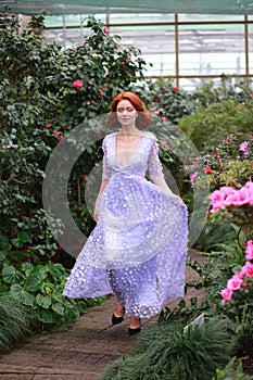 Red-haired girl in arranger where azalea blooms in a colorful flying dress photo