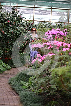 Red-haired girl in arranger where azalea blooms in a colorful flying dress photo