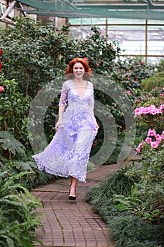 Red-haired girl in arranger where azalea blooms in a colorful flying dress