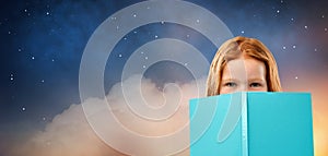 Red haired girl behind book over starry night sky