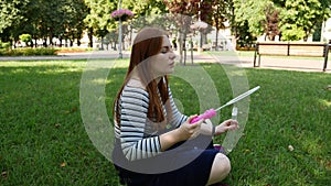 Red-haired girl blows soap bubbles in the park