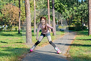 Red-haired girl with braids skates on pink rollers and falls in