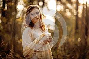 Red-haired girl in bright clothes on a background of autumn forest