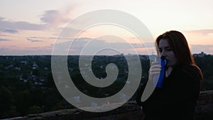 Red-haired girl  drinking tea from a thermocup