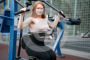 a red-haired girl is engaged in a sports simulator outdoors on a sports ground