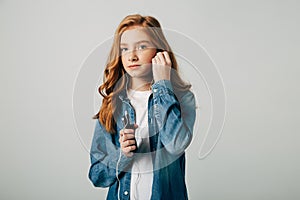 Red-haired girl listens to music in small headphones. She does not want to talk to her parents and turns on something on