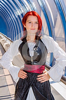 Red-haired girl in a long dress walks on the bridge