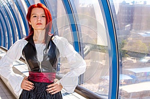 Red-haired girl in a long dress walks on the bridge