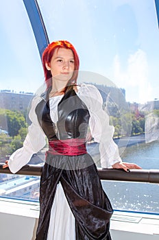 Red-haired girl in a long dress walks on the bridge