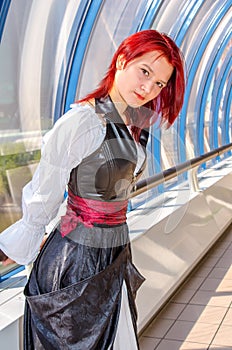 Red-haired girl in a long dress walks on the bridge