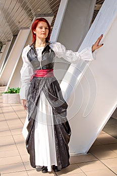 Red-haired girl in a long dress walks on the bridge
