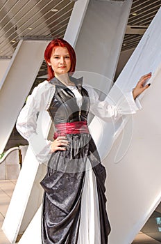 Red-haired girl in a long dress walks on the bridge