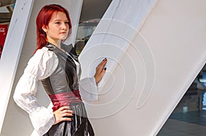 Red-haired girl in a long dress walks on the bridge