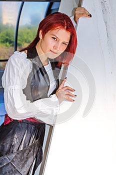 Red-haired girl in a long dress walks on the bridge