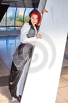 Red-haired girl in a long dress walks on the bridge