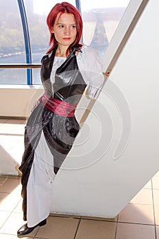 Red-haired girl in a long dress walks on the bridge