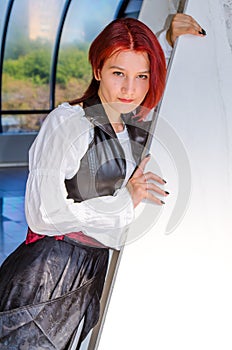 Red-haired girl in a long dress walks on the bridge