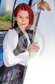 Red-haired girl in a long dress walks on the bridge