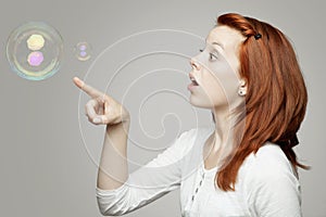 Red haired girl look to soap bubbles and wondering