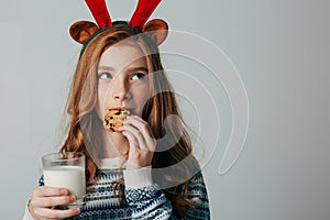 Red-haired girl with red horns in a sweater is very fond of milk with cookies a night. She did not wait for Santa and