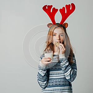 Red-haired girl with red horns in a sweater is very fond of milk with cookies a night. She did not wait for Santa and