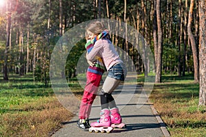 Red-haired girl on roller skates hugging boy in park.