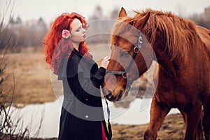 Red-haired girl stroking horse.