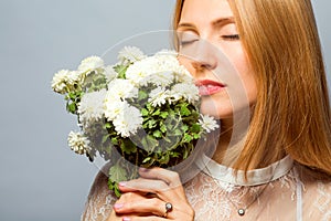 Red-haired girl in the studio with a white bouquet of flowers