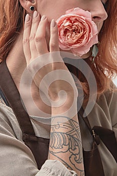 The red-haired girl with a tattoo is holding a pink rose in her mouth. Layout for postcard