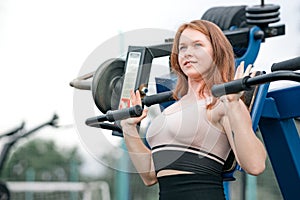 red-haired girl trains on a sports simulator outdoors