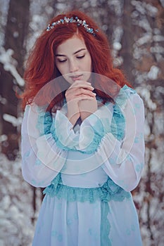 Red-haired girl walking on a cold winter forest.
